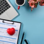 Health insurance claim form, computer, coffee, and flowers.