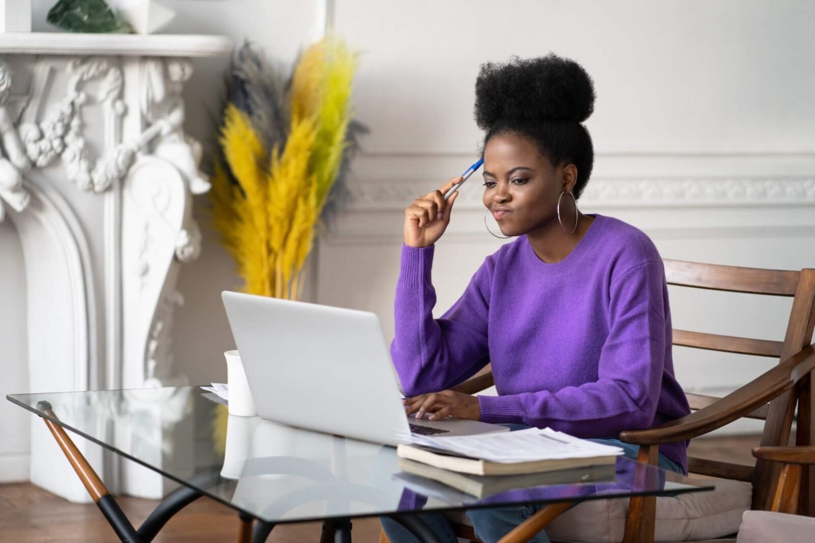 A woman sits at a desk looping at a laptop screen. She has a perplexed look on her face.