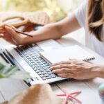 This is a close up of a woman's hands at a keyboard. She appears to be booking a trip.