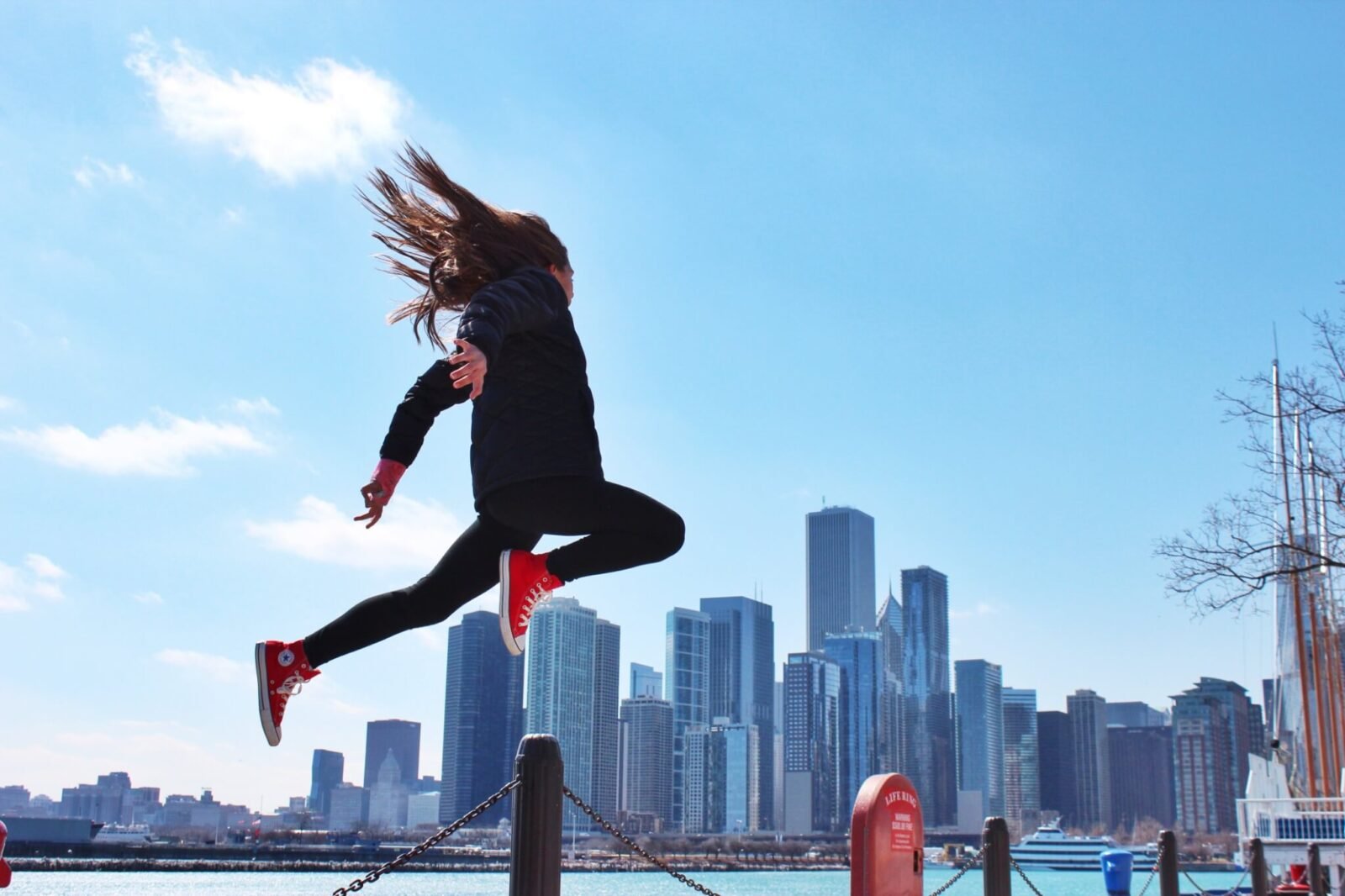 This is an image of a woman jumping in the air. The backdrop is a city.