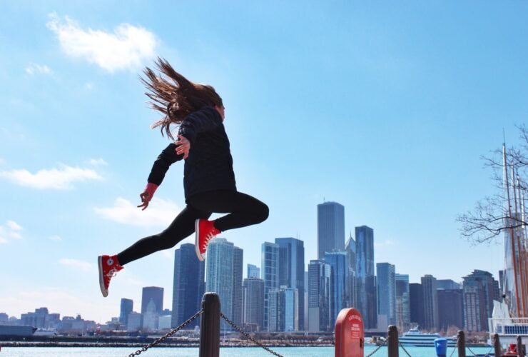 This is an image of a woman jumping in the air. The backdrop is a city.