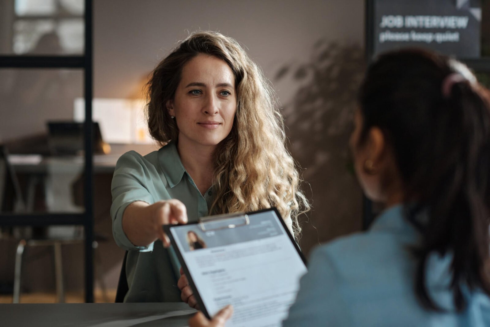 women handing her resume in at interview