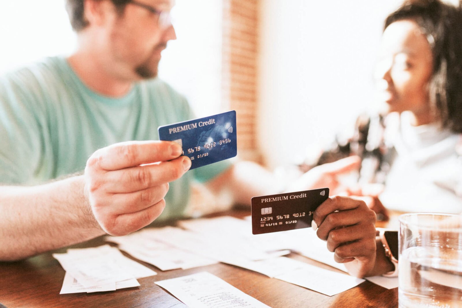 A couple sits at the kitchen table reviewing their monthly bills as they discuss the Best Debt Repayment Methods
