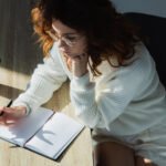 women writing in notebook with coffee