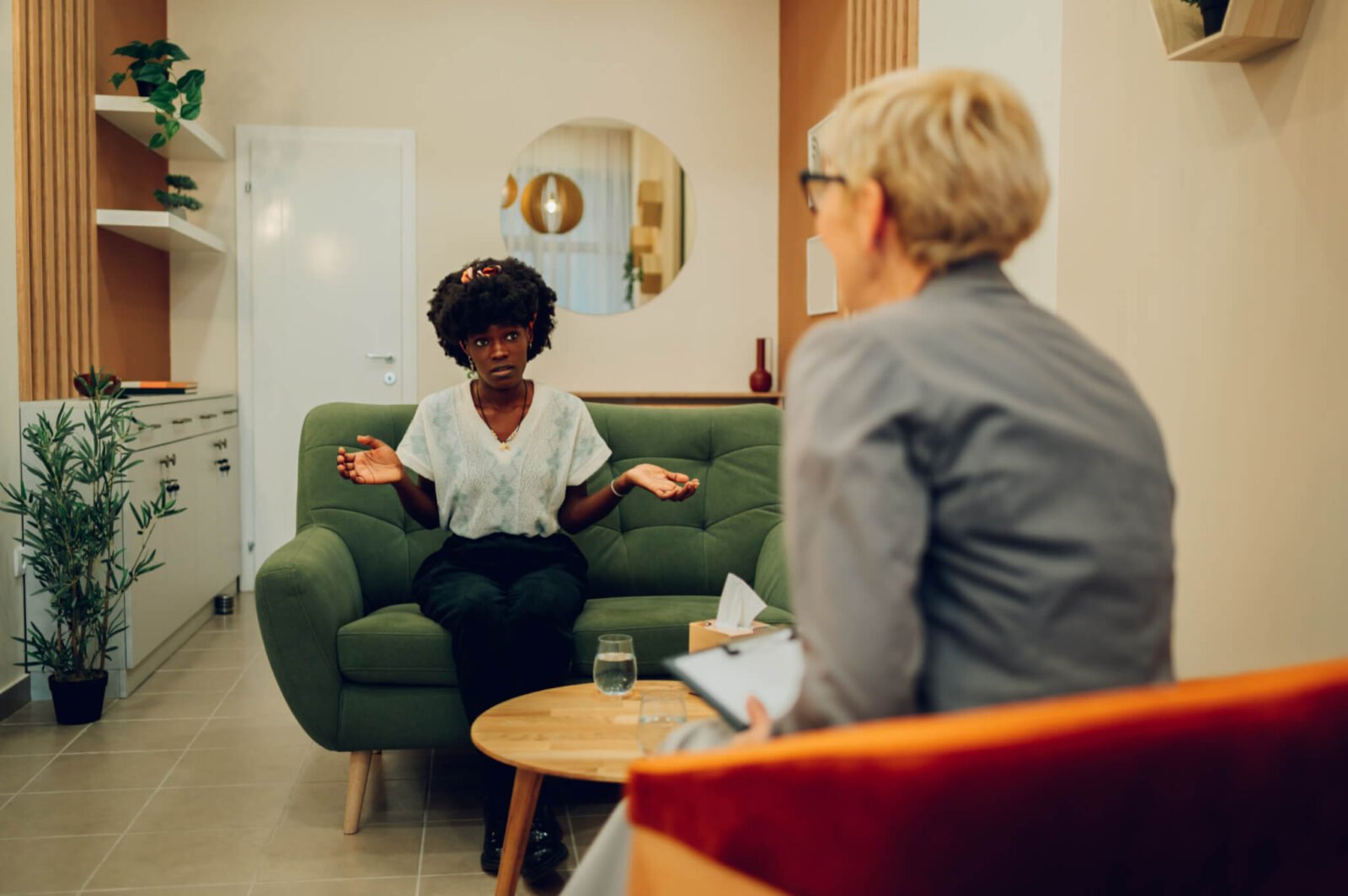 Women in therapy with arms raised talking to a psychologist.