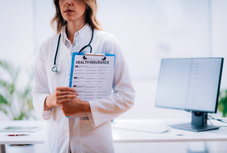 woman in lab coat holds health insurance form