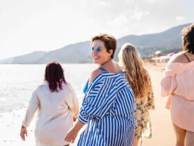 Women walking on the beach wearing sunglasses and smiling.