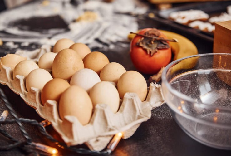 Carton of eggs on a counter with vegetables