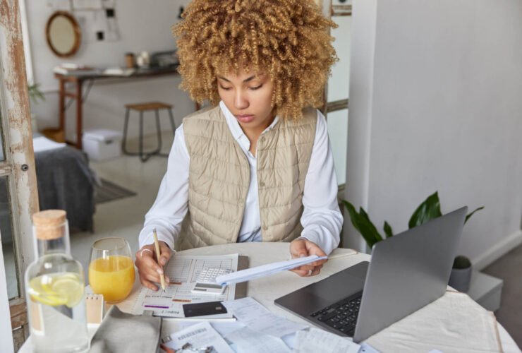 woman sits at table and balances her budget