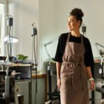 A female small business owner stands in her studio wearing an apron.