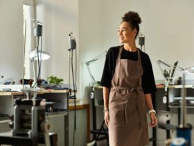 A female small business owner stands in her studio wearing an apron.