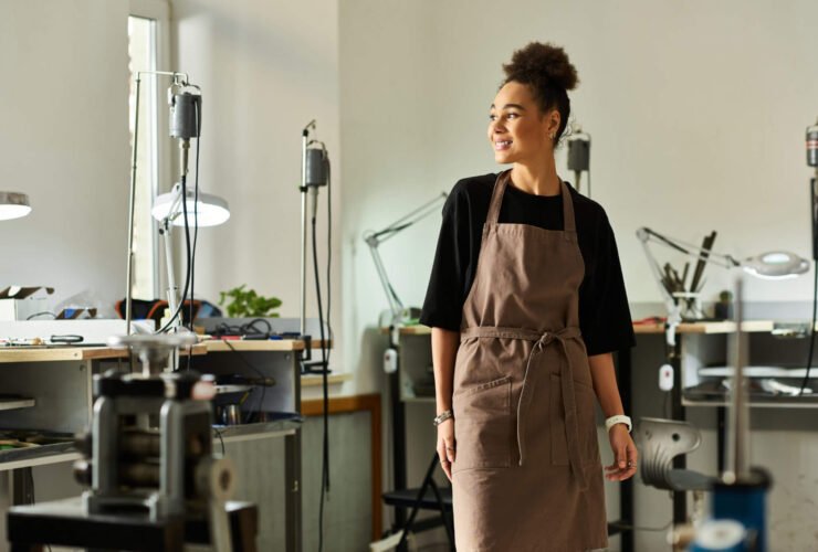 A female small business owner stands in her studio wearing an apron.