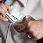 This is a close up of a woman putting money in her pocket.