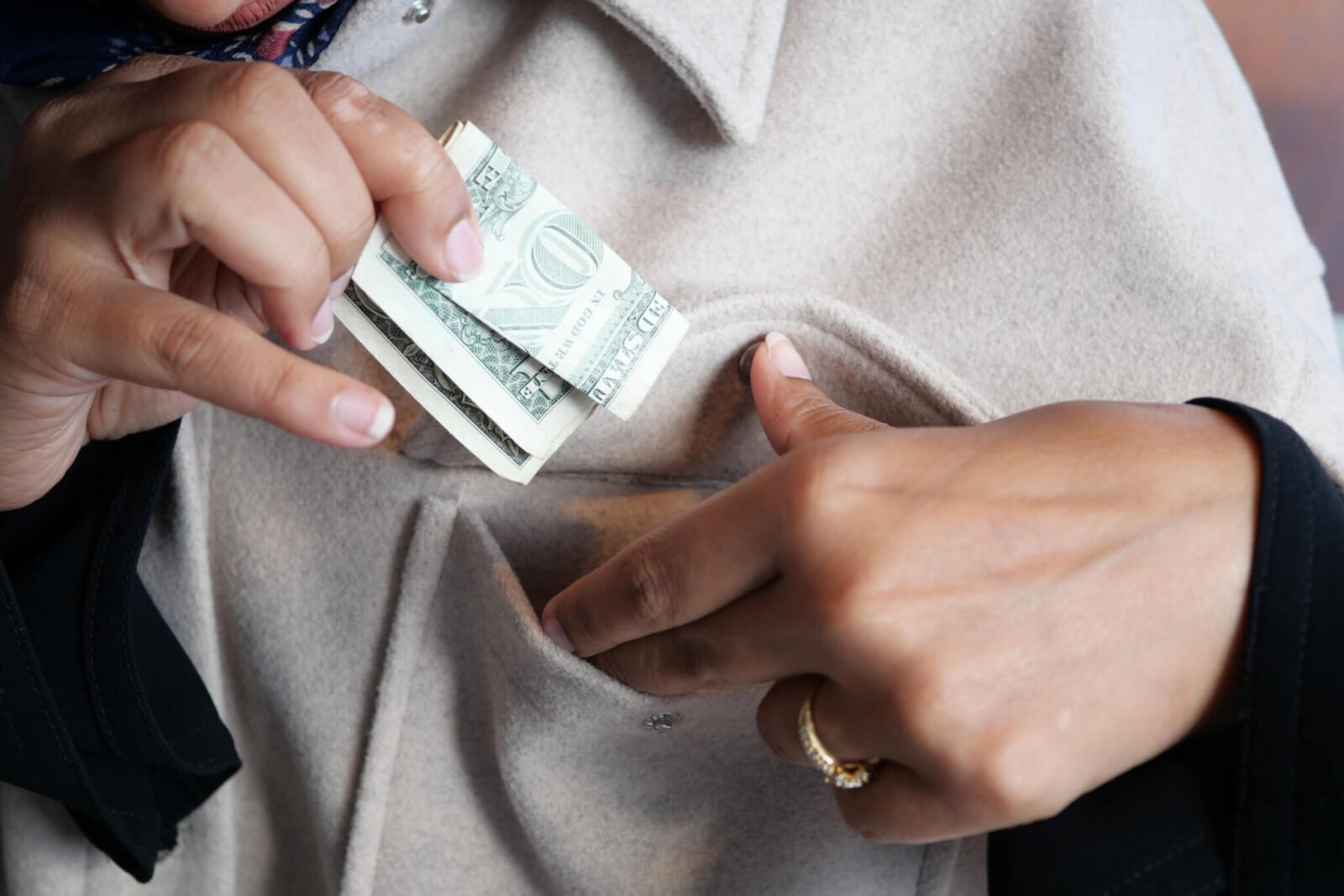 This is a close up of a woman putting money in her pocket.