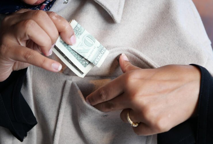 This is a close up of a woman putting money in her pocket.