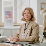 woman leading local government sitting at a table with a vote sign in the background