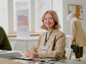 woman leading local government sitting at a table with a vote sign in the background
