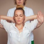 chiropractor working on woman putting arms behind the head