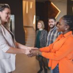 two women shake hands at work
