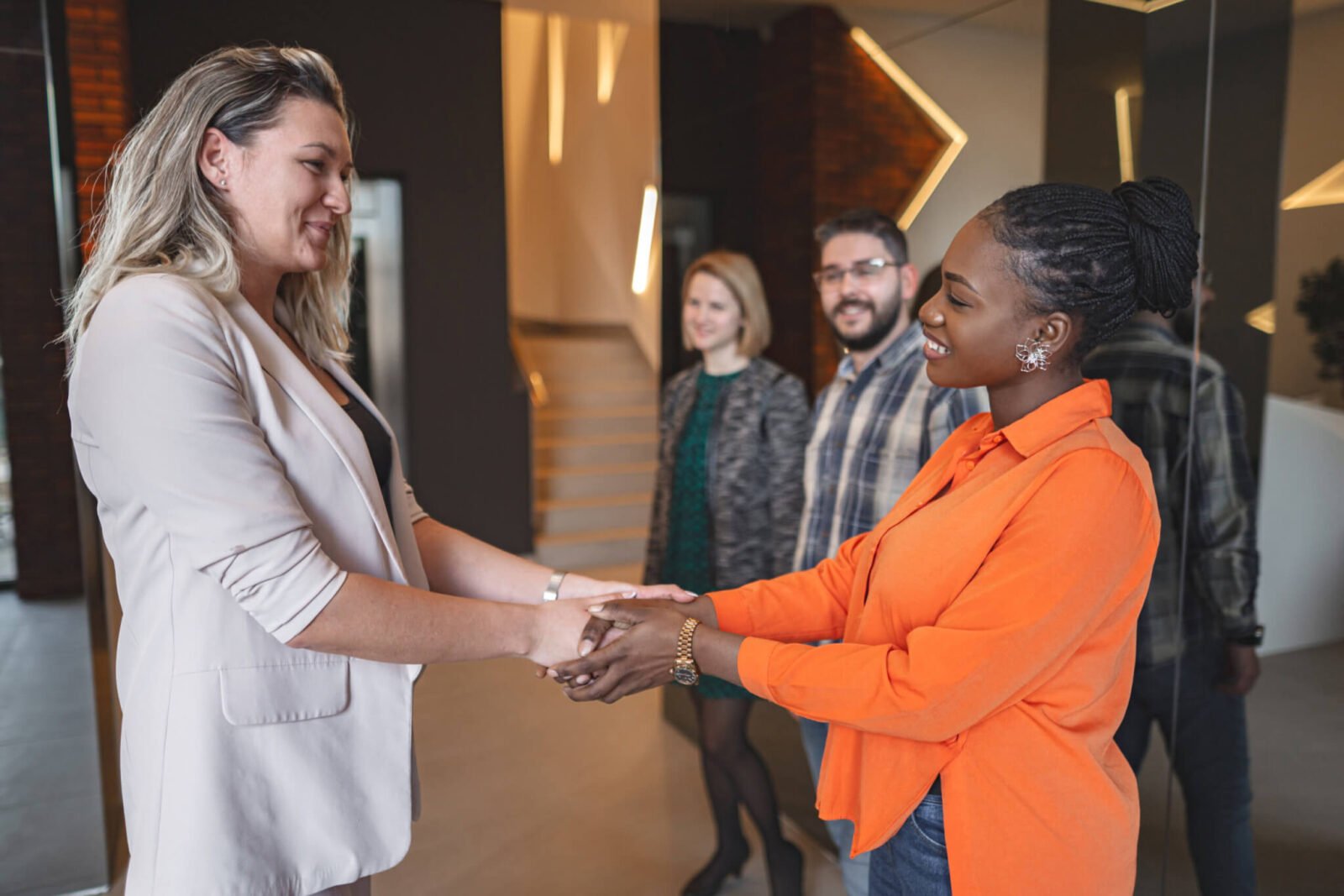 two women shake hands at work