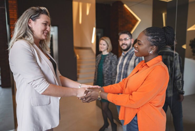 two women shake hands at work