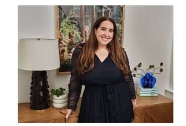 Sami Sage of Betches Media stands and smiles at the camera wearing a black dress.
