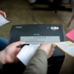 This is a photo depicting people putting documents into a shredder
