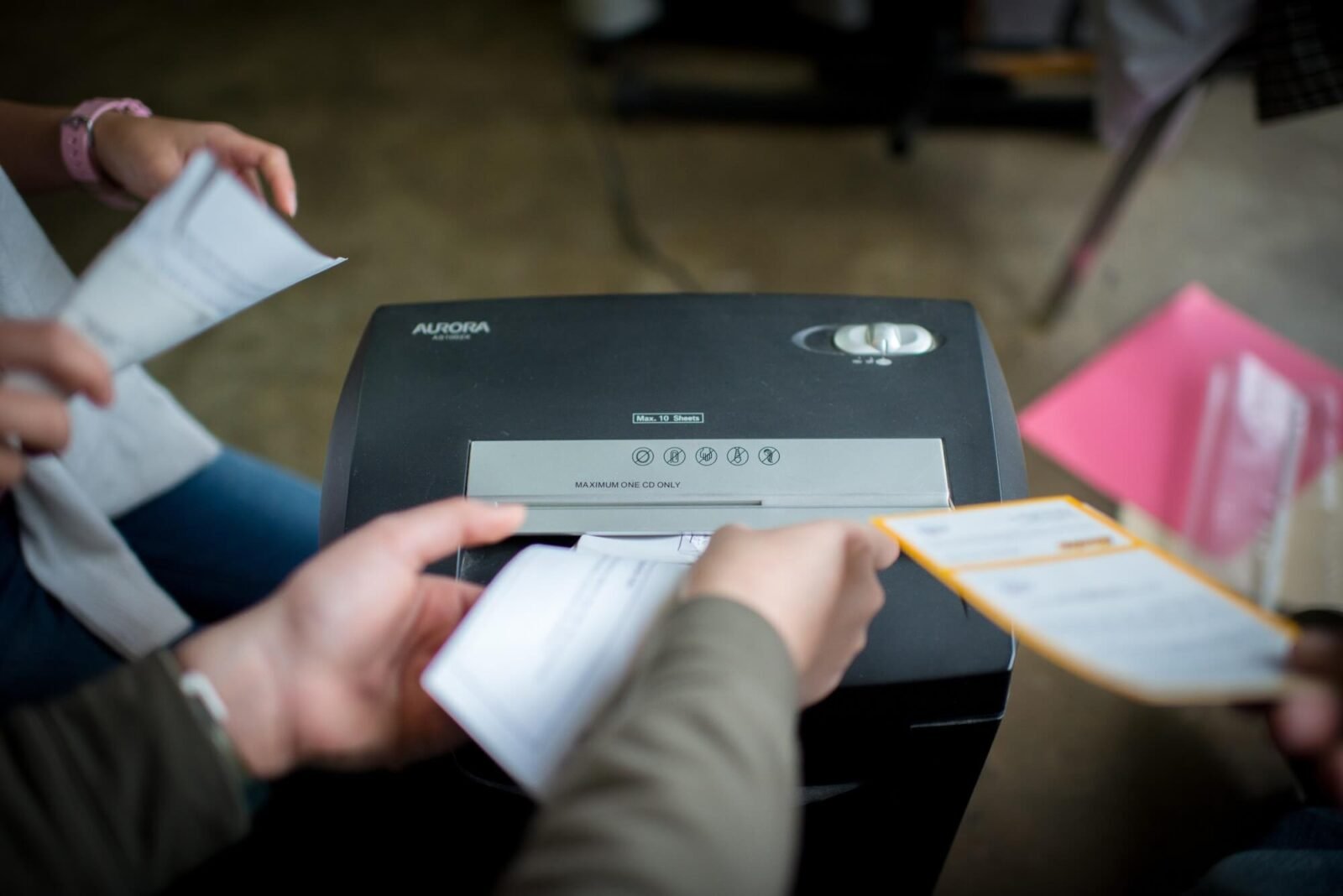 This is a photo depicting people putting documents into a shredder