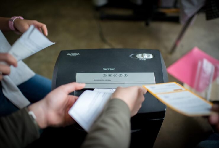 This is a photo depicting people putting documents into a shredder